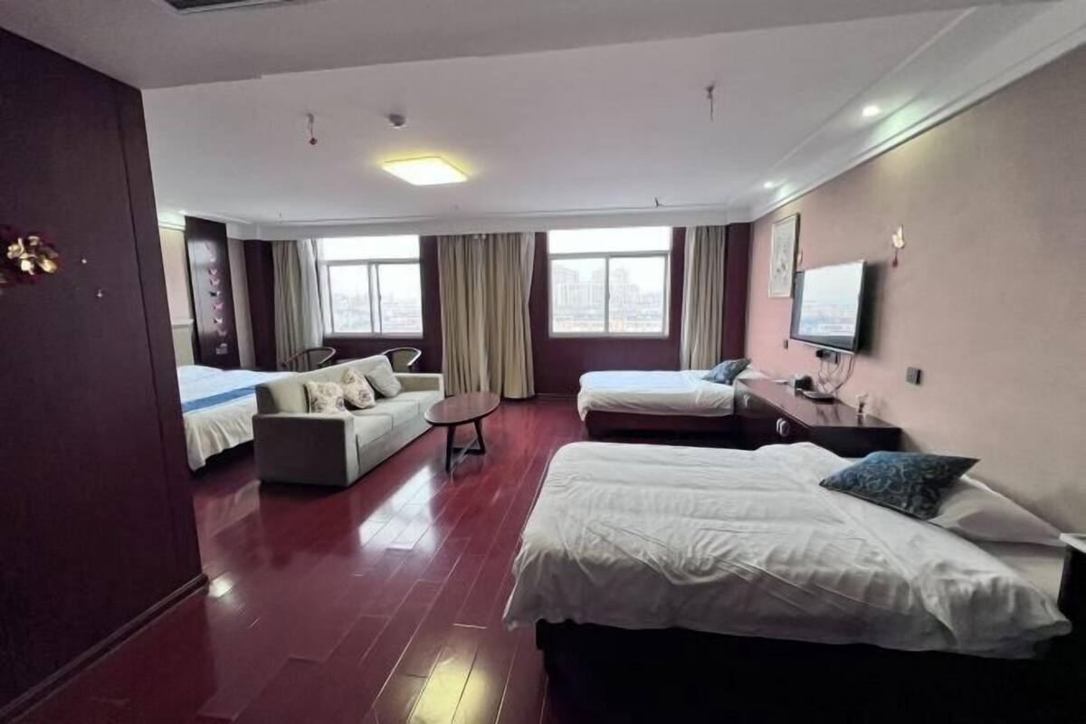 Une chambre d’hôtel avec deux lits, un canapé, une télévision et une fenêtre avec des rideaux.