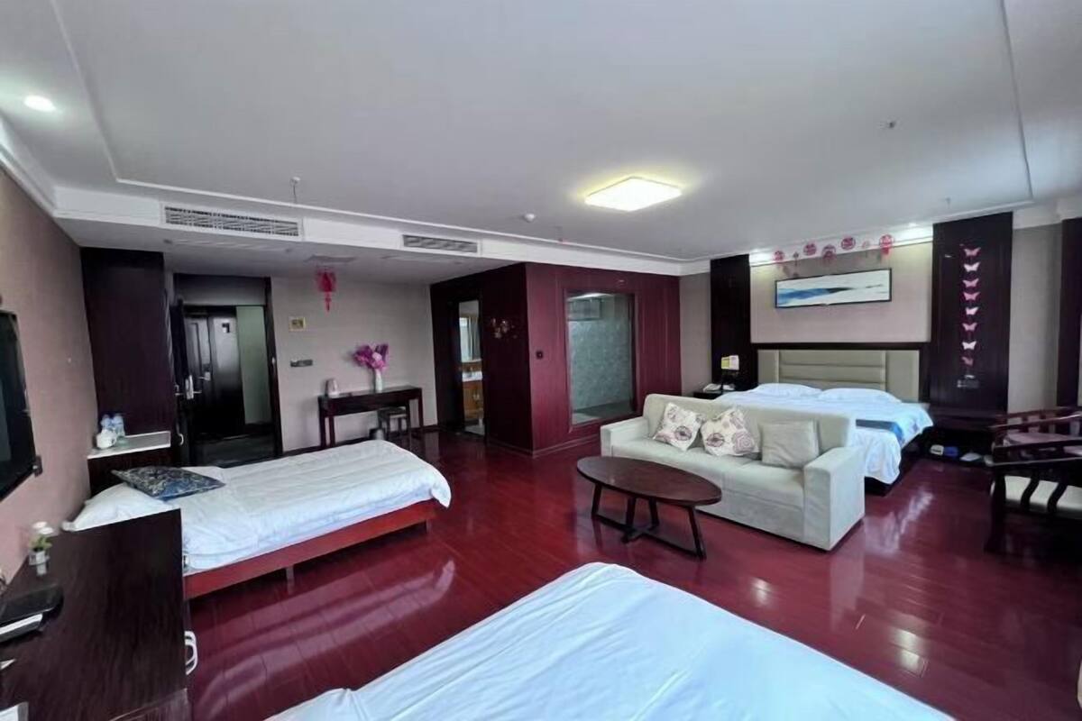 Une chambre d’hôtel avec deux lits, un canapé, une petite table et un téléviseur.