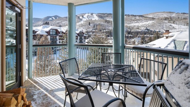 A balcony with a table and chairs, overlooking a snowy mountain landscape. - Beaver Creek Village Ski In, Ski Out 2 Bedroom Residence With Pool (Avon)