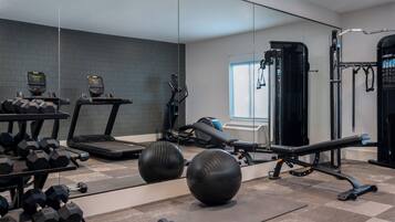 Un gimnasio con cintas de correr, pesas, balones de ejercicio y una estructura para sentadillas.