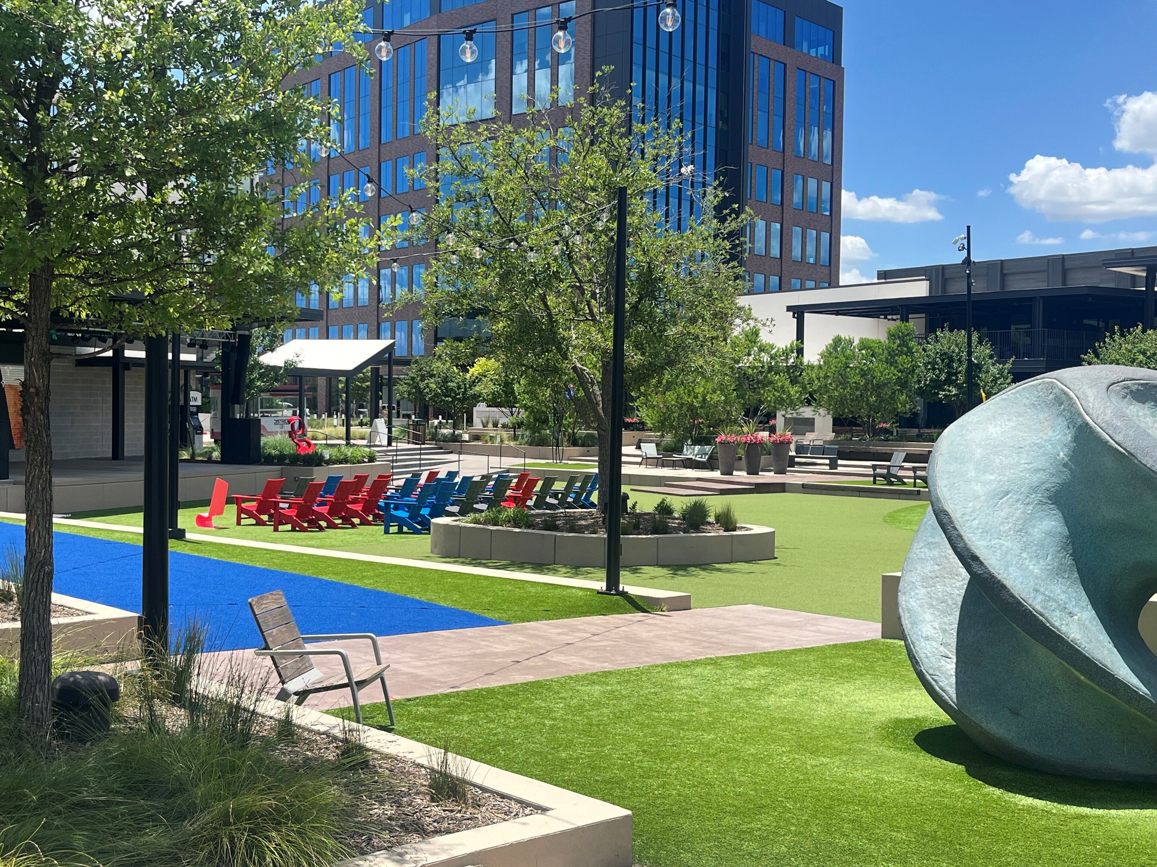 A modern outdoor area with a pool, lounge chairs, and a large sculpture.