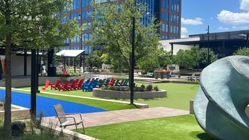 A modern outdoor area with a pool, lounge chairs, and a large sculpture.