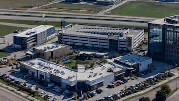 Vue aérienne d’un ensemble immobilier commercial comprenant plusieurs parkings, un parking central en sous-sol et des immeubles de bureaux adjacents.