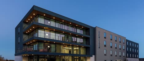 A modern hotel with a two-story structure, large windows, and a well-lit entrance.