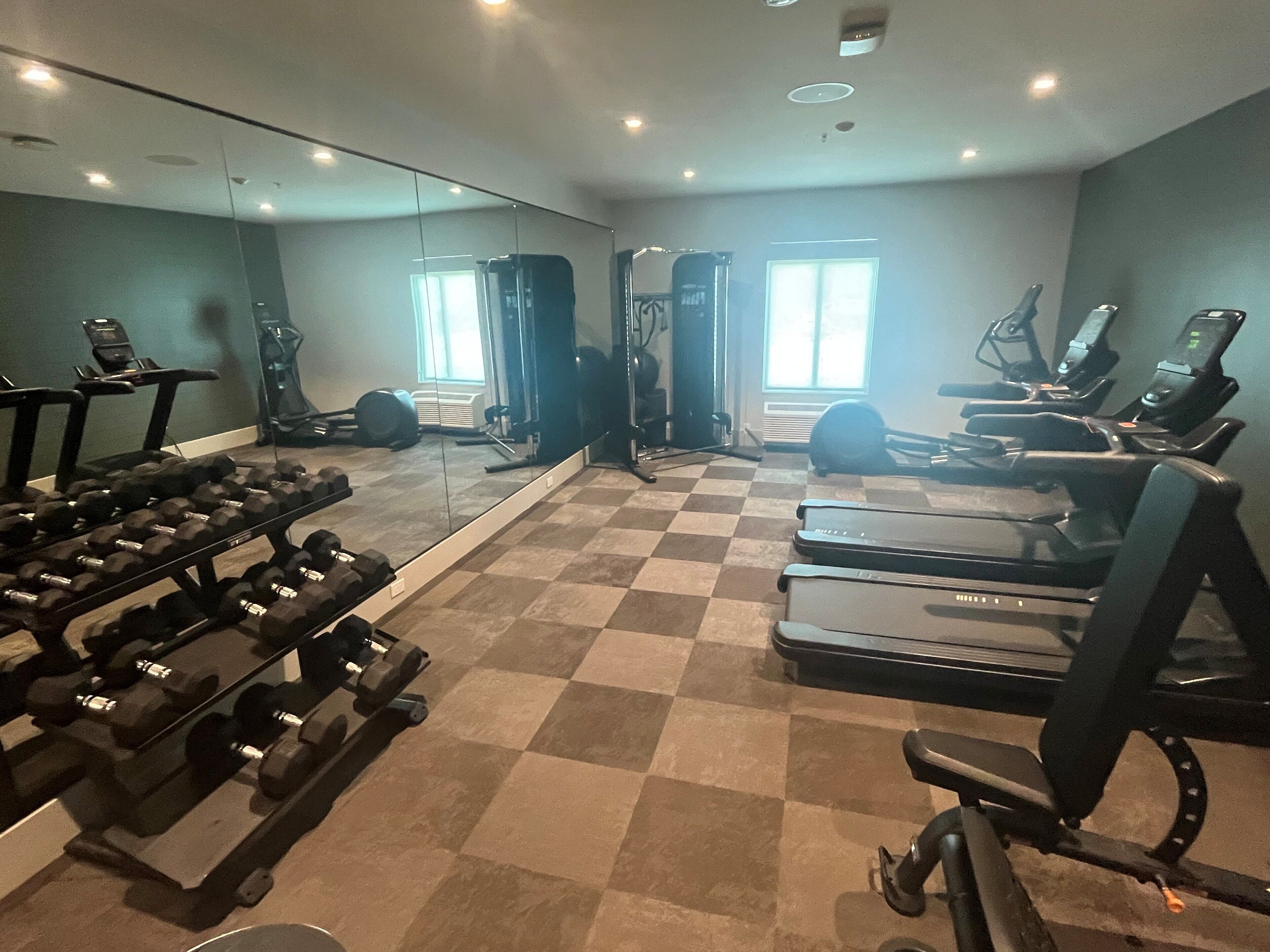 Een sportschool met loopbanden, elliptische trainers en losse gewichten.