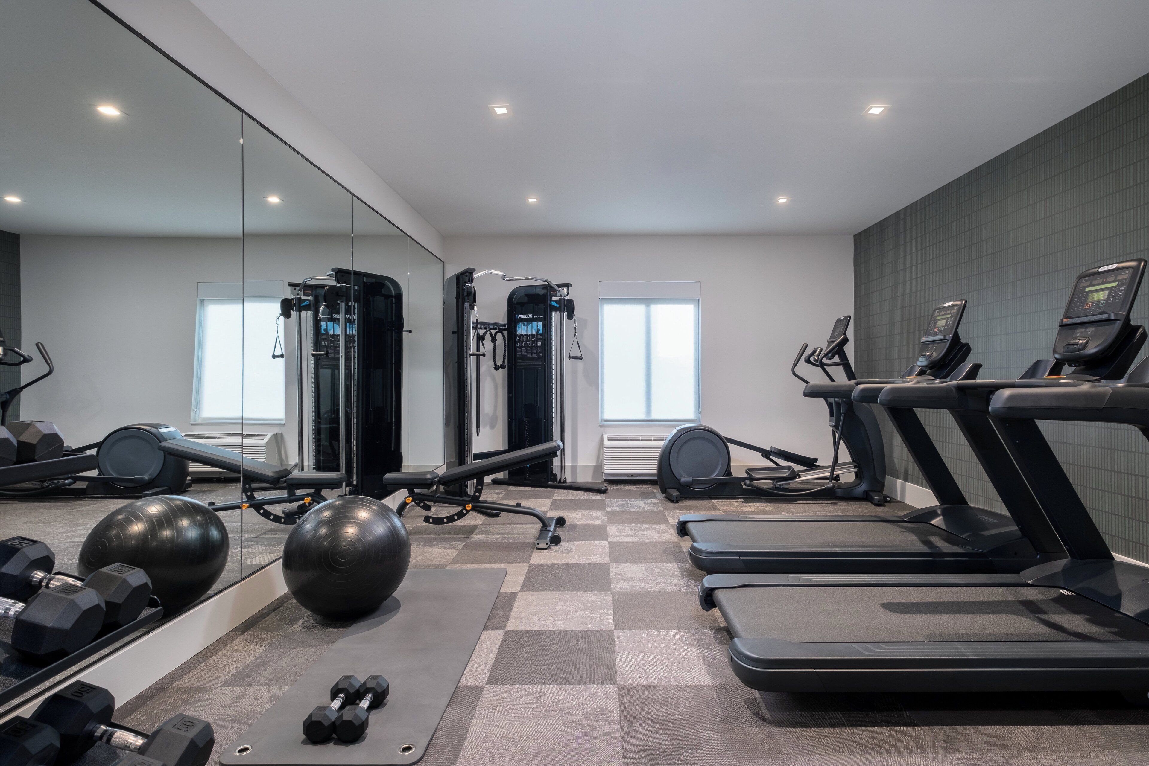A modern gym with treadmills, exercise balls, and free weights.