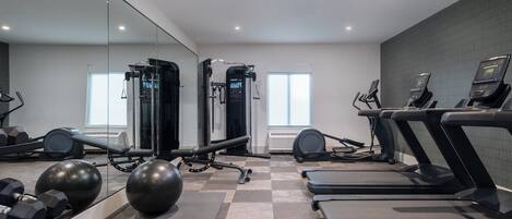 A modern gym with treadmills, exercise balls, and free weights.