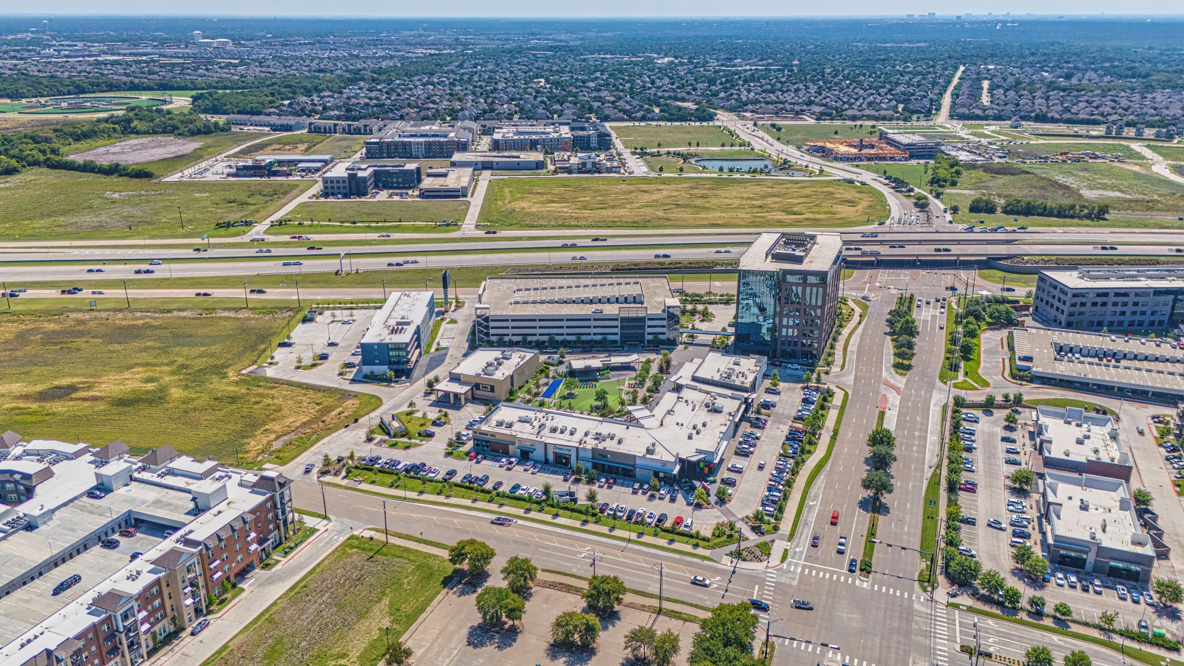 Vista aérea de una zona comercial con varios edificios, estacionamientos y calles.