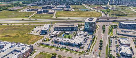 Vista aérea de una zona comercial con varios edificios, estacionamientos y calles.