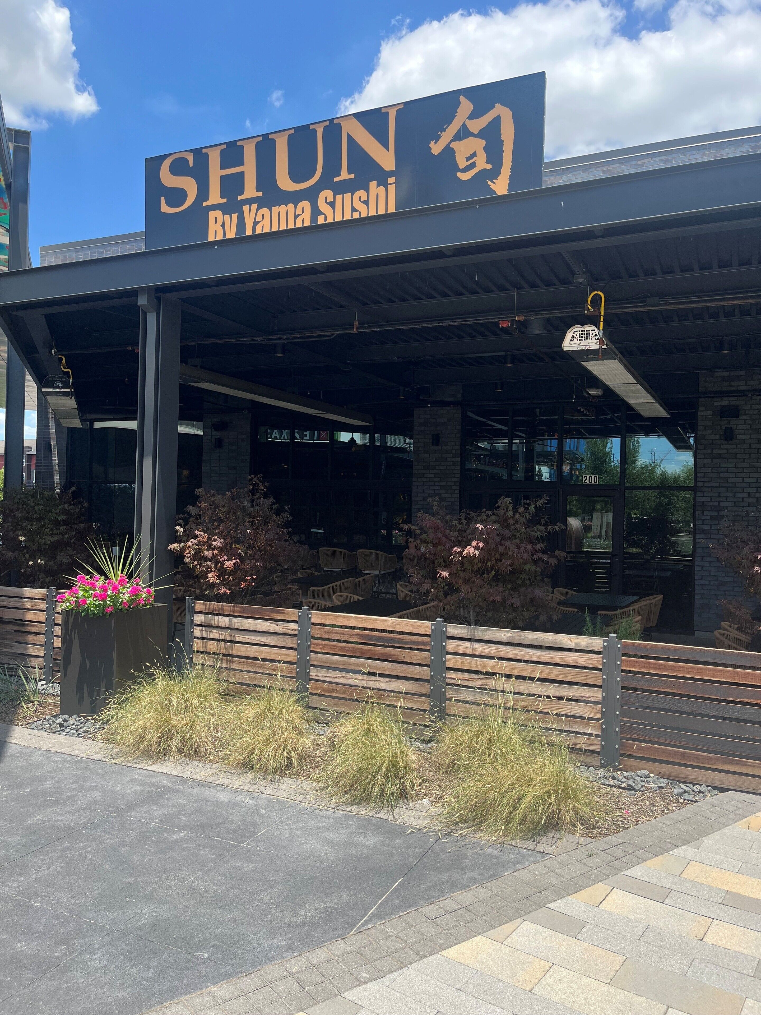 Un restaurante llamado SHUN con terraza al aire libre y un patio cubierto.
