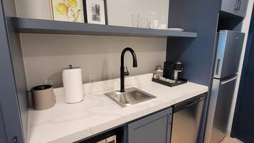 A modern kitchen with a sink, a coffee maker, and a microwave.