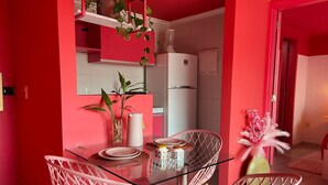 Una cocina moderna con una mesa de vidrio, sillas rosas y un refrigerador blanco.