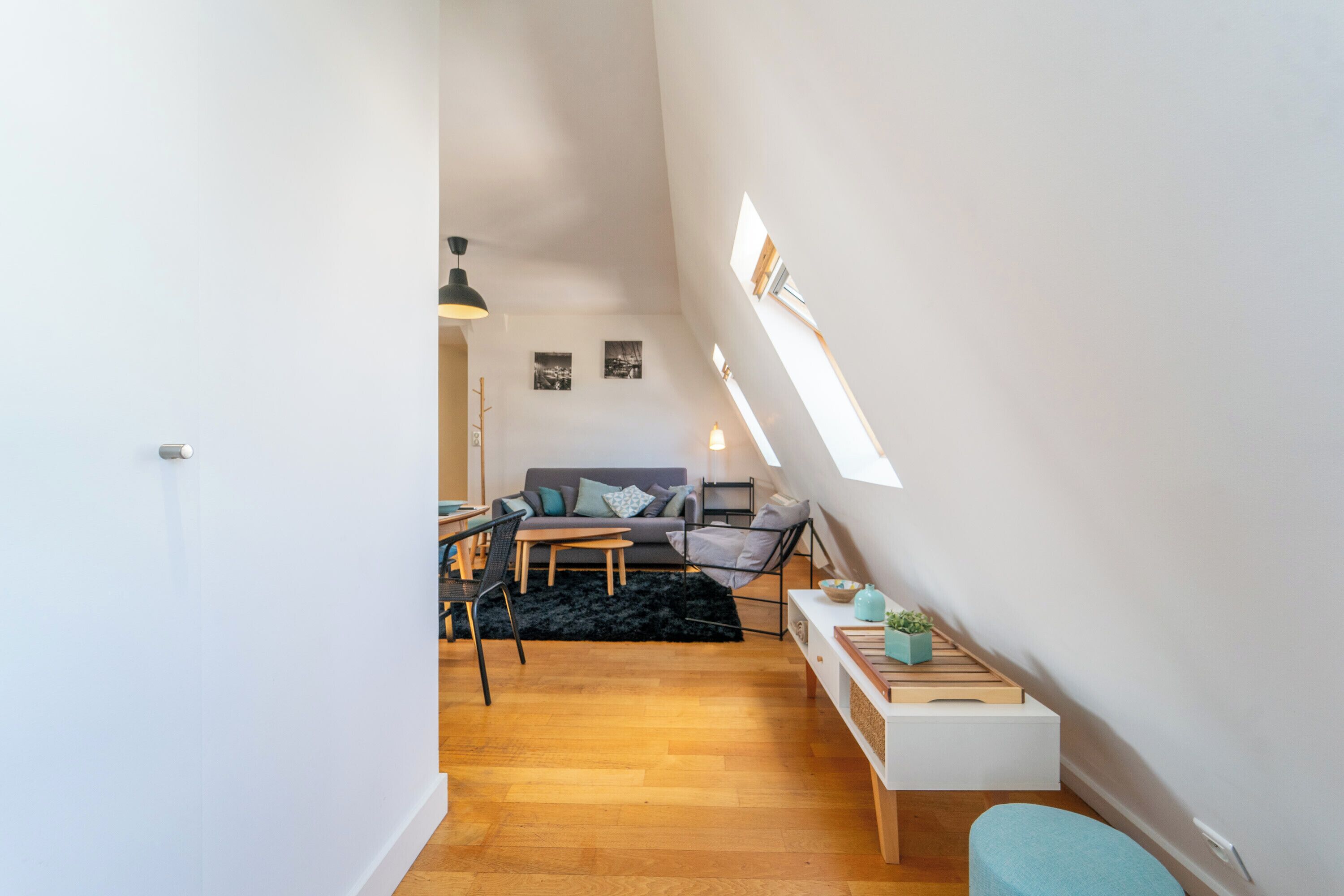 Un espacio habitable compacto con un entrepiso para dormir, un sofá, una mesa de comedor y una mesita auxiliar pequeña.
