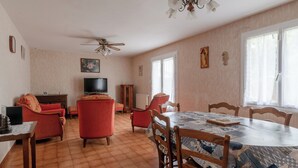 Un coin repas comprenant une table ronde, des chaises, un ventilateur de plafond et un téléviseur.