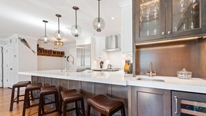 A modern kitchen with a large island, bar stools, stainless steel appliances, and pendant lighting. - Beaver Creek Residences - 2 Bedroom Luxury Ski In/out Condo (Avon)