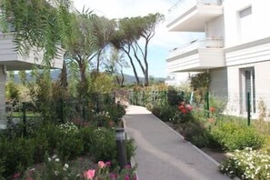Stunning residential building with a flat facade and balcony, set amidst lush gardens and a serene pathway.
