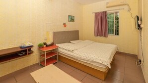 A bedroom with a bed, a desk, a chair, a shelf, and a window with curtains.