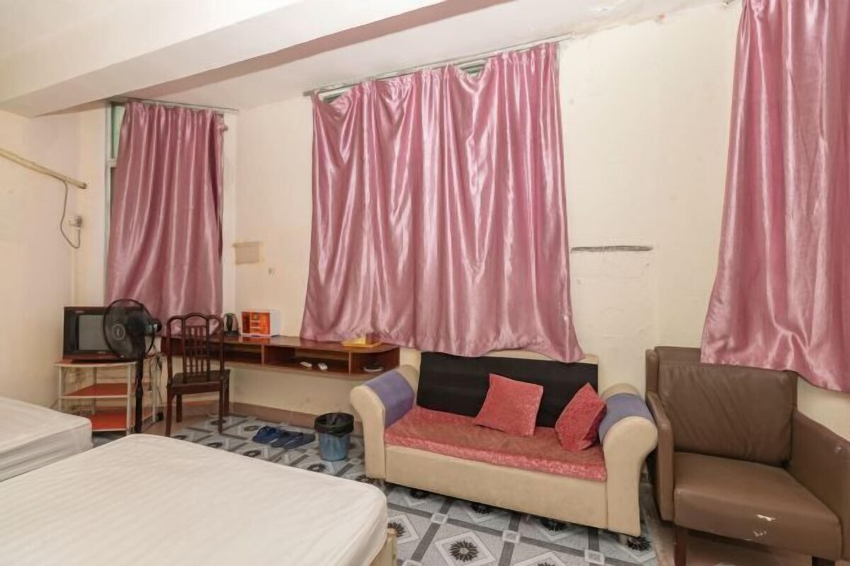 A room with a bed, a sofa, a desk with a chair, and a television.