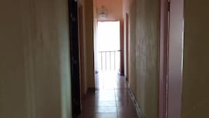 A narrow hallway with tiled flooring and doors on both sides.