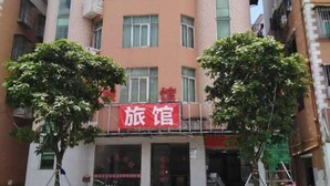 A hotel with a red sign, multiple floors, and balconies.