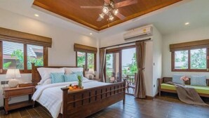 A bedroom with a wooden bed, a nightstand, a ceiling fan, and large windows. - Lanna Deer Chiang Mai (Hang Dong)