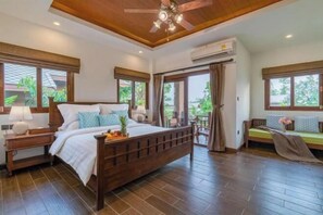 A bedroom with a wooden bed, a nightstand, a ceiling fan, and large windows. - Lanna Deer Chiang Mai (Hang Dong)