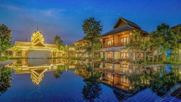 A resort with a large reflective pool, traditional architecture, and a well-lit building. - Lanna Deer Chiang Mai (Hang Dong)