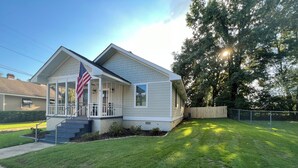 A single-story house with a front porch, a small front yard, and a wooden fence. - Charming Game Day House  (Opelika)