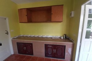 Une cuisine avec des meubles de rangement en bois, un plan de travail et une porte.