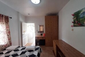 A bedroom with a bed, a wooden bench, a desk, a wardrobe, and a painting on the wall. - Parichat house (Pak Chong)