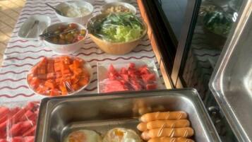 A buffet table with various food items including eggs, sausages, and vegetables.