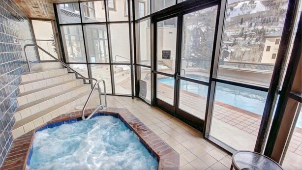A hot tub area with a view of a pool and a staircase leading to an outdoor area. - Beaver Creek Village 2 Bedroom Residence With Ski In/out Access and Pool (Avon)