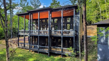 A view of the cabin exterior, highlighting a large deck that overlook the forest