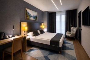 Quarto de hotel moderno com cama, escrivaninha, cadeira e um quadro na parede.