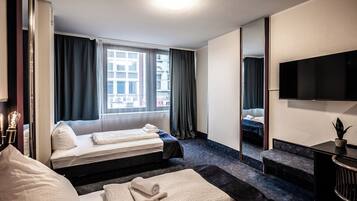 A hotel room with two beds, a TV, a mirror, and a window with curtains.