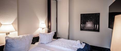 Habitación de hotel con cama doble, dos lámparas de noche, un espejo grande y un cuadro en la pared.
