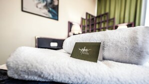 A neatly made bed with a fluffy white blanket and a card that reads "Hotel Mirage." - Hotel Mirage Düsseldorf-Neuss (Neuss)