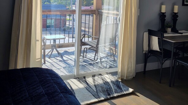 A room with a large sliding glass door leading to an outdoor patio, a bed, a table with chairs, and framed pictures on the wall. - Our 2nd Studio at The Lofts in Hesperia.
 (Hesperia)