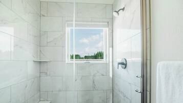 A bathroom with marble tiles, a window, and a shower area.