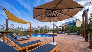 Eine Holzterrasse mit Liegestühlen und einem Pool.