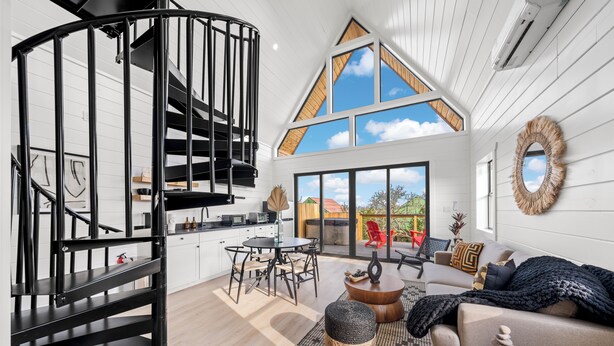 Ein modernes Interieur mit einer Wendeltreppe, einem Essbereich und einem Wohnzimmer mit großem Fenster.