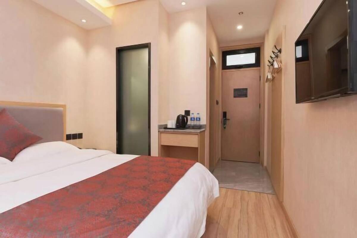 A hotel room with a bed, a desk, a coffee machine, and a TV.