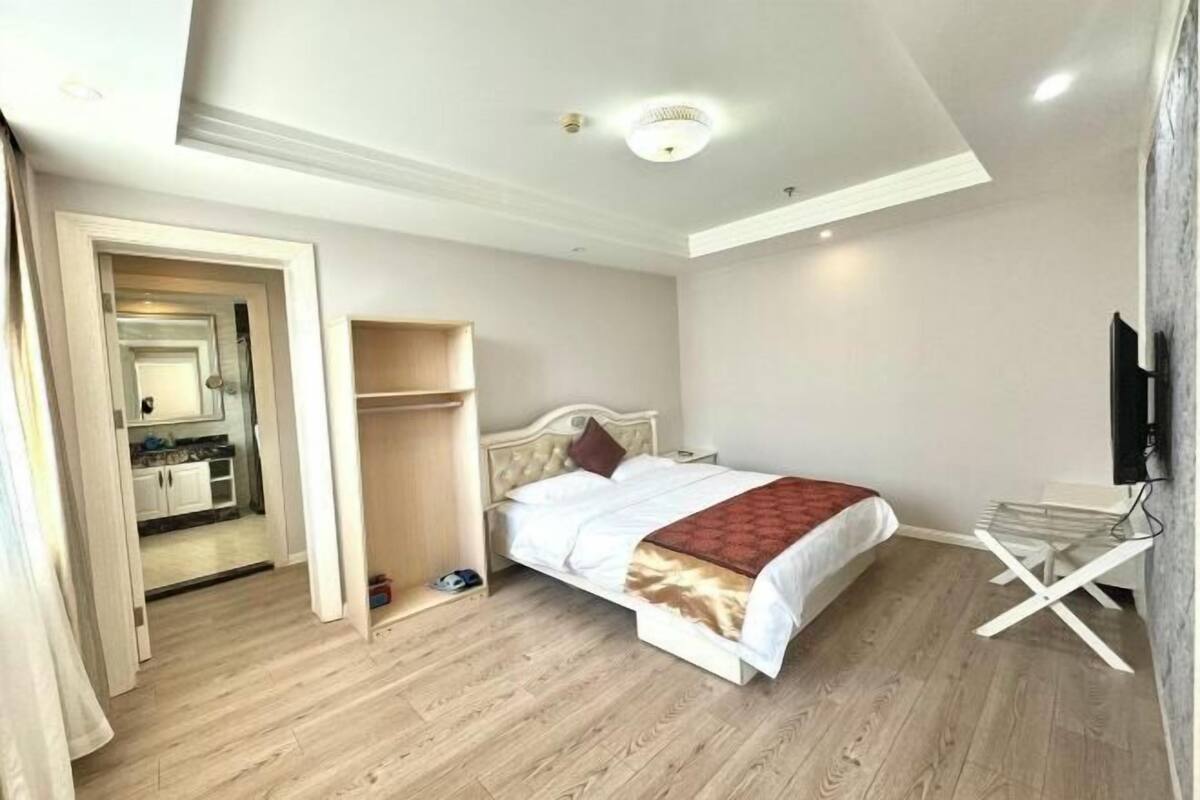 A bedroom with a bed, a wardrobe, a TV, and a small seating area.
