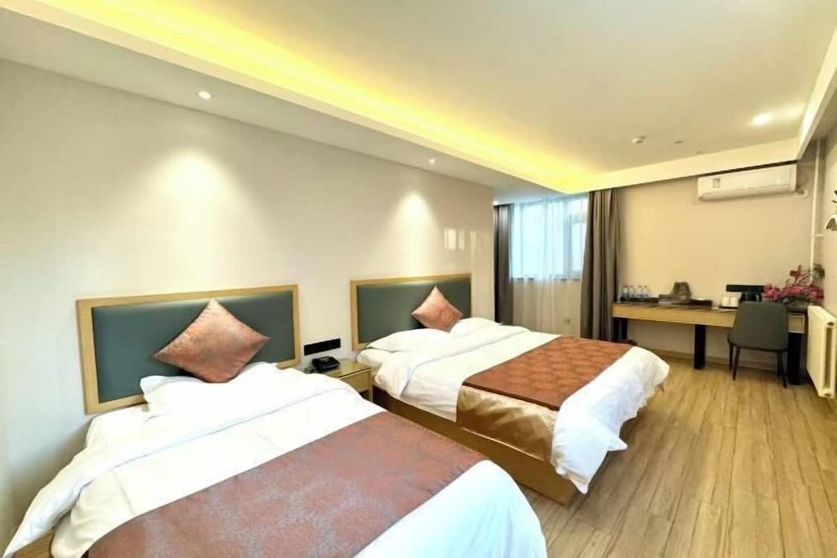 A hotel room with two beds, a desk, and a chair.