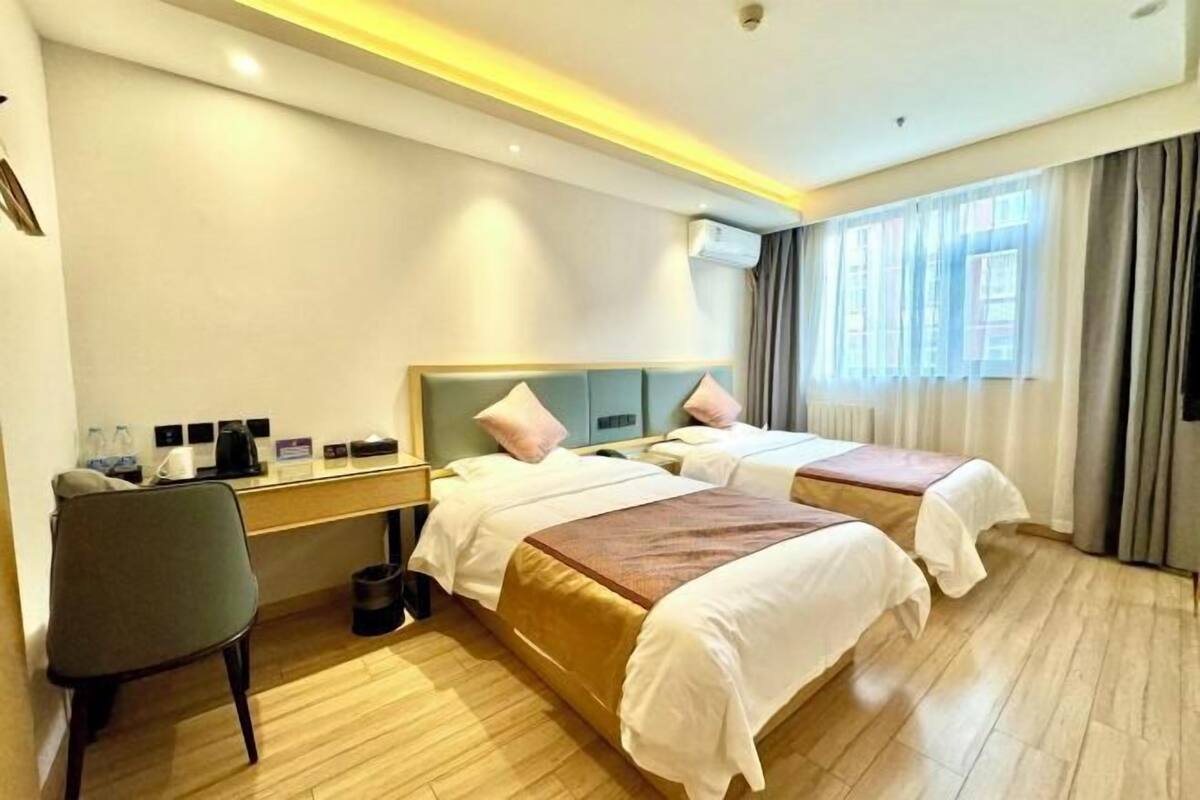 A hotel room with two beds, a desk, and a chair.