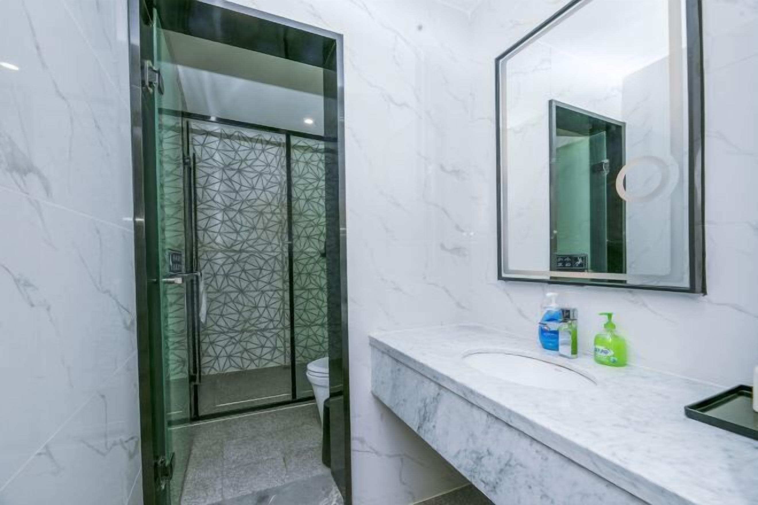 A modern bathroom with a glass-enclosed shower, a marble countertop, and a large mirror.