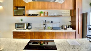 Une cuisine moderne avec des meubles en bois, un four à micro-ondes encastré, une machine à café, un grille-pain et un mixeur.