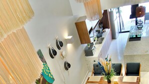 Un salon moderne comprenant un canapé, une table à manger et des chaises. Il y a également un coin cuisine avec un réfrigérateur et un évier.