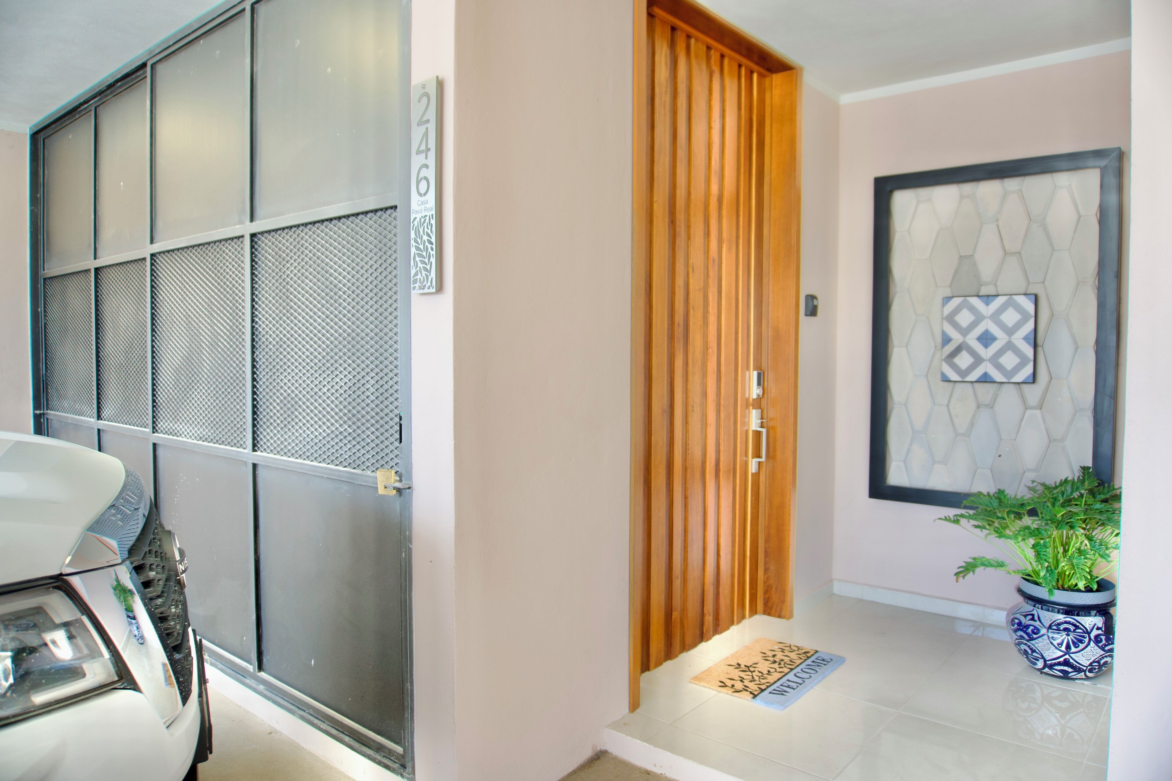A modern entrance with a sliding door, a welcome mat, and a potted plant.