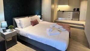 Une chambre à coucher moderne avec un grand lit, des tables de chevet et un mur d’accent de couleur foncée.